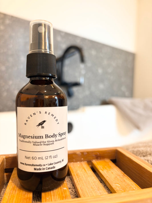 Bottle of Raven's Remedy Magnesium Body Spray on a wooden tray with a blurred bathroom background.